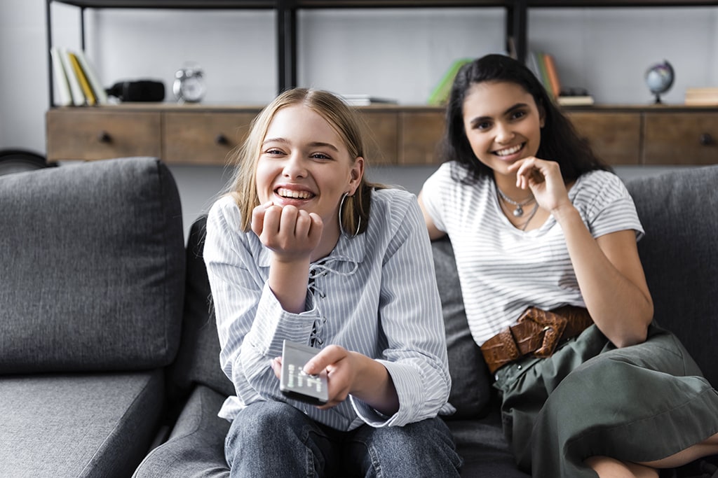 Two teenage girls watching residential IPTV on couch