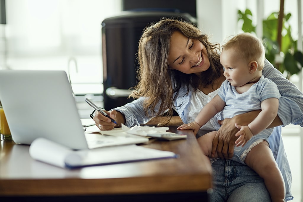 Young mother working at home with baby on lap