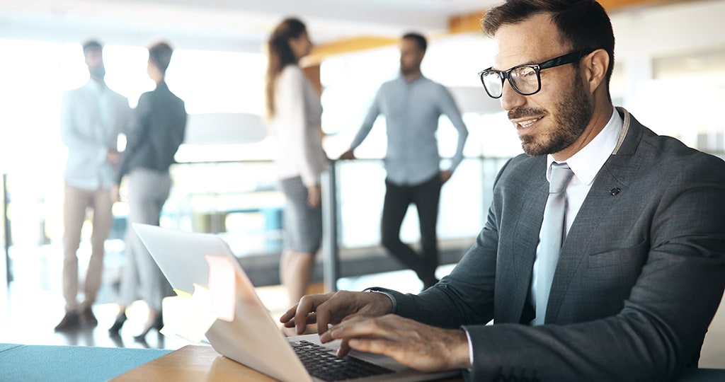 Man using the internet for business on his laptop in an office